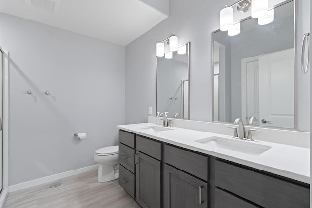 bathroom with toilet, vanity with extensive cabinet space, and dual sinks