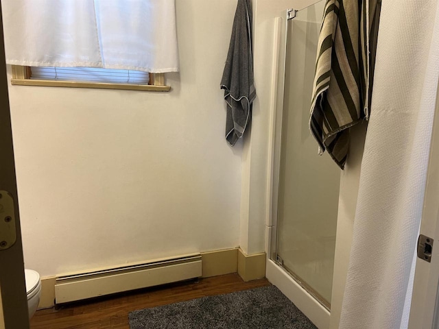 bathroom featuring hardwood / wood-style flooring, a baseboard radiator, toilet, and an enclosed shower