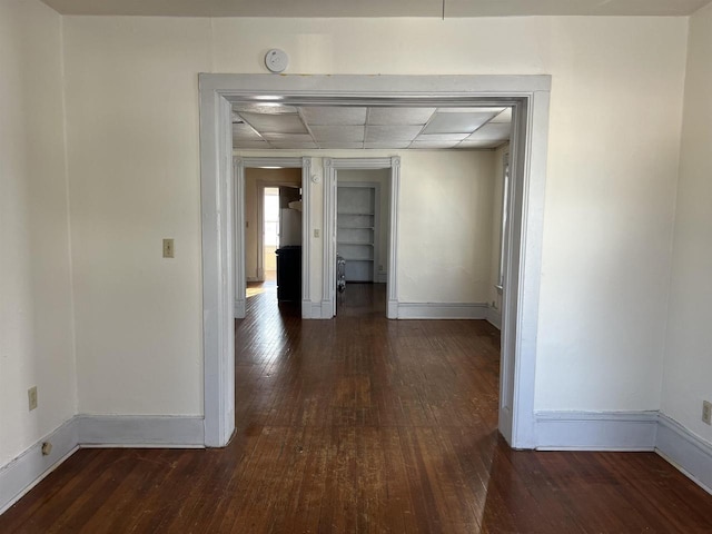 corridor with a paneled ceiling and dark hardwood / wood-style floors