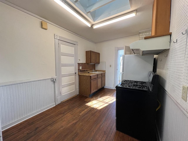 kitchen with white refrigerator, dark wood-type flooring, sink, and black gas range