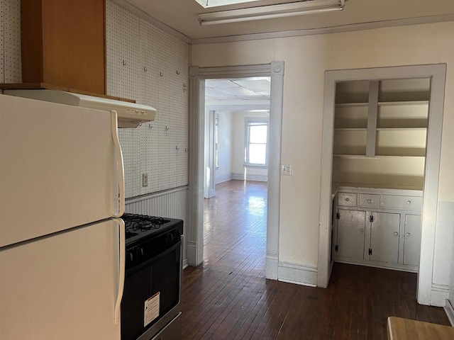 kitchen featuring built in shelves, dark wood-type flooring, stainless steel gas range oven, white refrigerator, and white cabinets