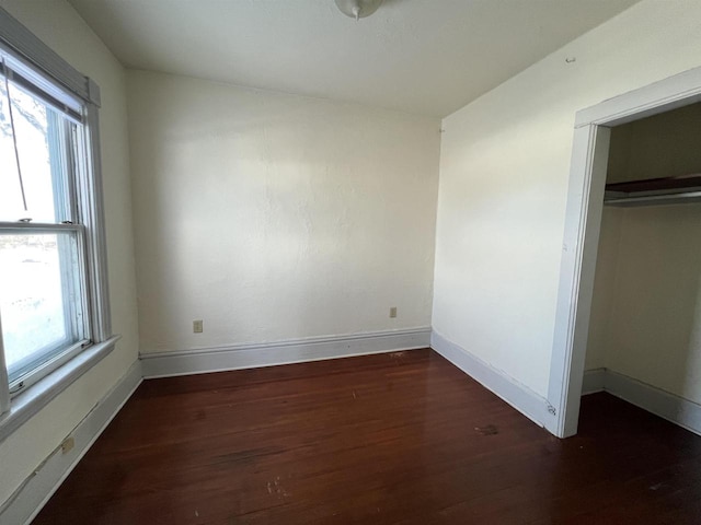 unfurnished bedroom featuring dark wood-type flooring and a closet