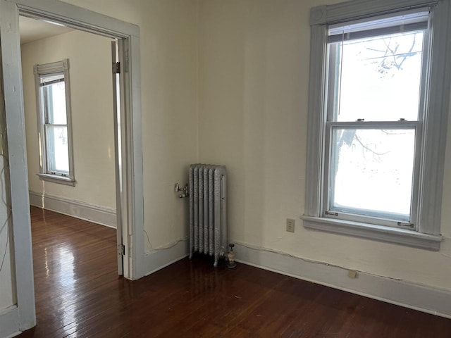 empty room featuring radiator heating unit and dark hardwood / wood-style flooring