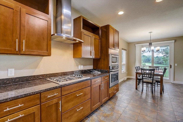 kitchen with pendant lighting, stainless steel appliances, wall chimney range hood, tile floors, and an inviting chandelier