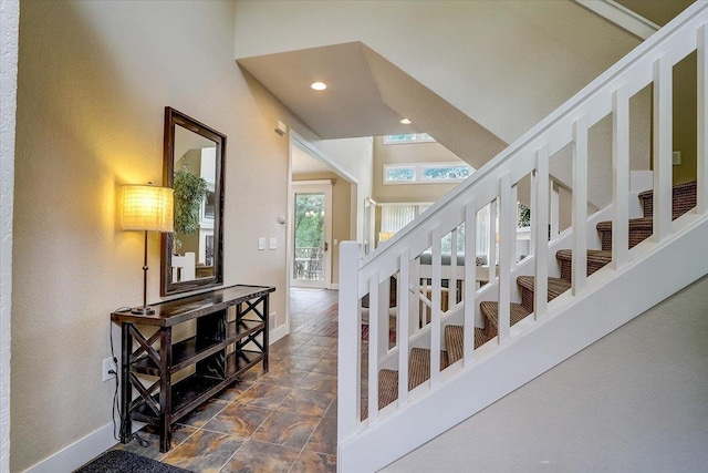 stairway featuring high vaulted ceiling and dark tile flooring