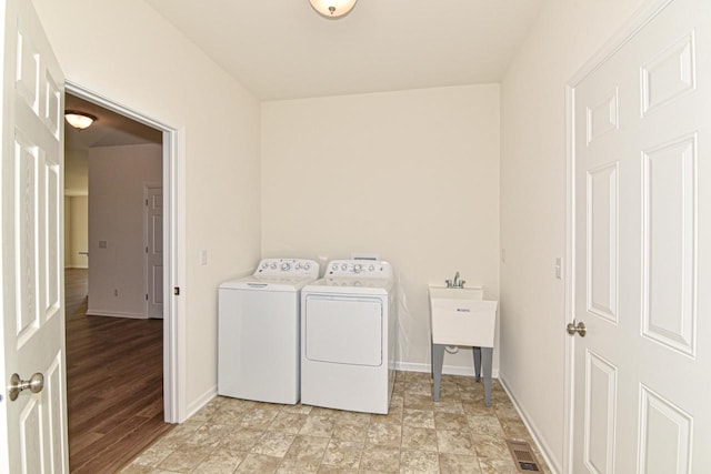 clothes washing area with light wood-type flooring and separate washer and dryer