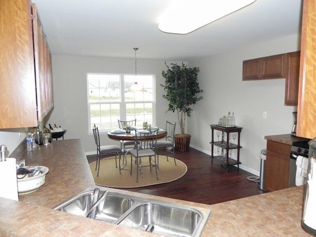 kitchen featuring stainless steel range, dark hardwood / wood-style floors, sink, and decorative light fixtures