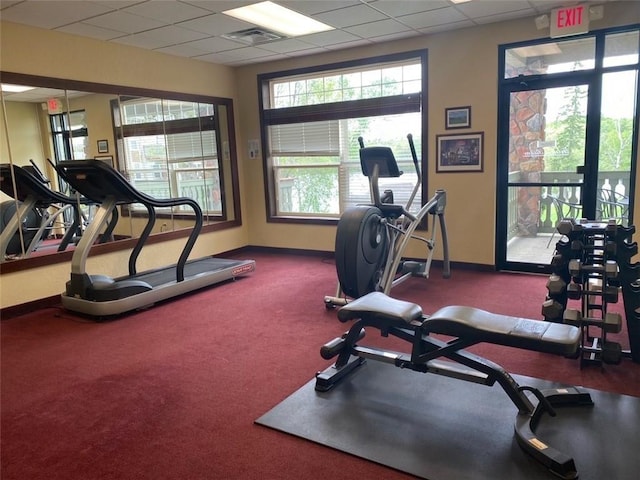 workout area featuring dark carpet and a drop ceiling