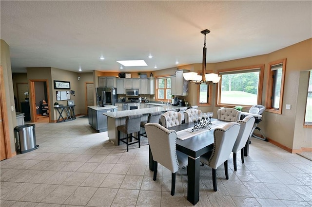 dining area featuring light tile floors, a skylight, and a chandelier