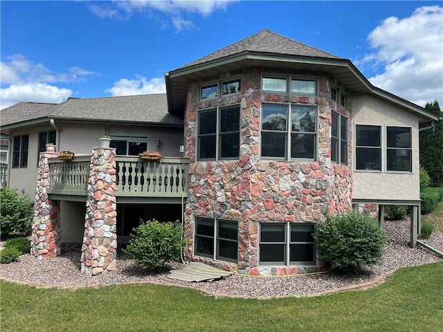 back of house featuring a balcony and a yard