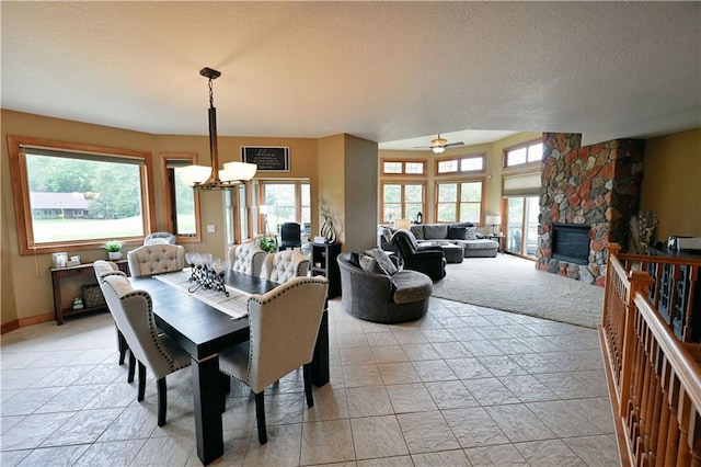 tiled dining area featuring a textured ceiling, ceiling fan with notable chandelier, a fireplace, and a wealth of natural light