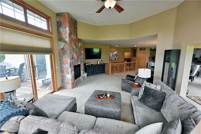 carpeted living room featuring ceiling fan, a fireplace, and a high ceiling