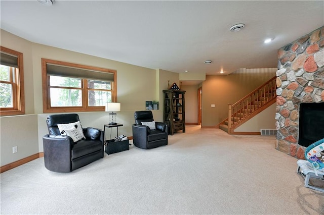 carpeted living room featuring a stone fireplace