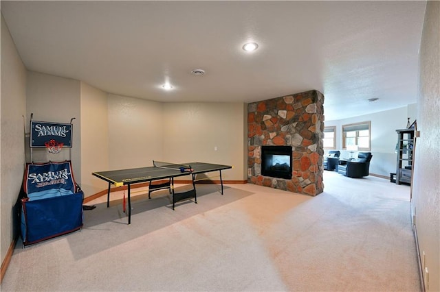 game room with light carpet and a stone fireplace