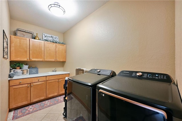 laundry area featuring light tile flooring, sink, cabinets, and washer and clothes dryer