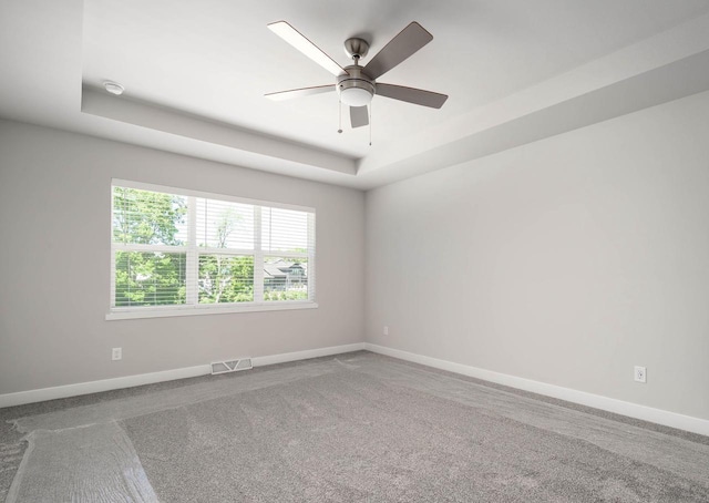 carpeted empty room featuring a raised ceiling and ceiling fan