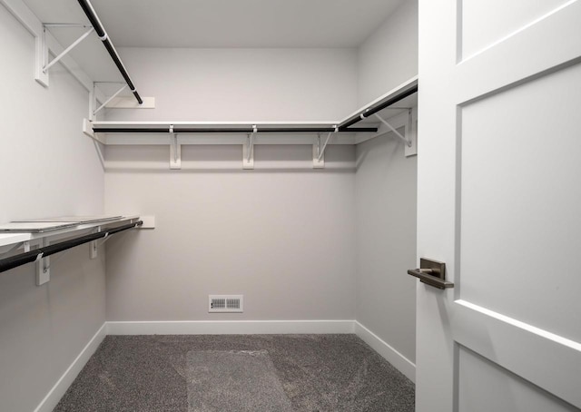 walk in closet with dark carpet