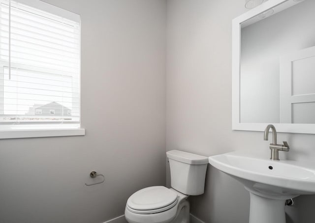 bathroom with a healthy amount of sunlight, toilet, and sink