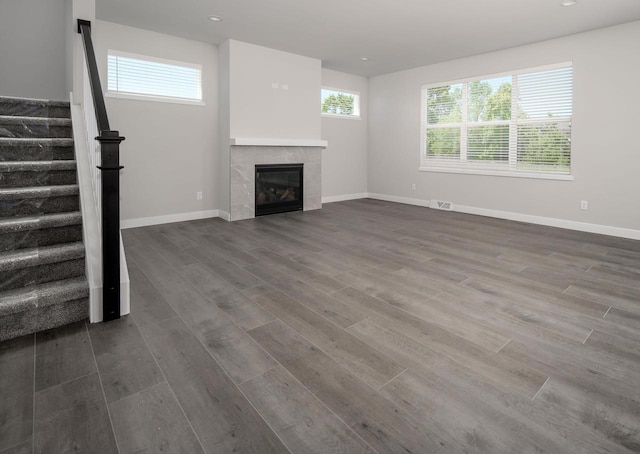 unfurnished living room with a tiled fireplace and dark hardwood / wood-style floors