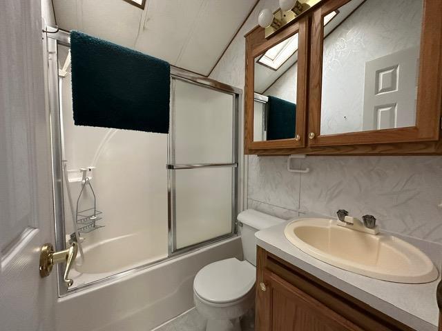 full bathroom featuring enclosed tub / shower combo, tile patterned flooring, vanity, toilet, and lofted ceiling