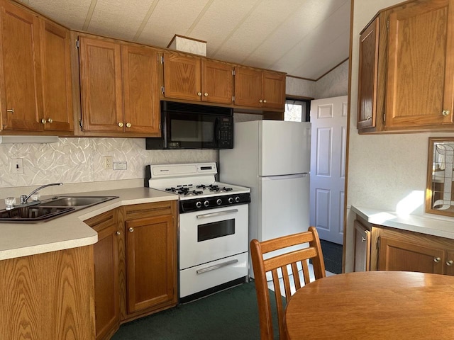 kitchen with sink, white appliances, and dark carpet