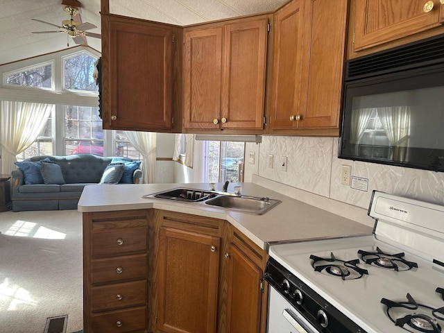 kitchen featuring ceiling fan, sink, kitchen peninsula, carpet floors, and white range oven