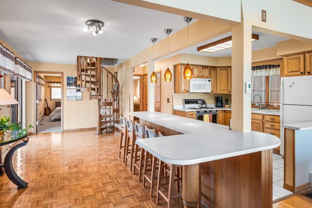 W1188 Spring Grove Rd, Green Lake, WI 54971 - kitchen with white appliances, a kitchen breakfast bar, sink, light parquet floors, and pendant lighting