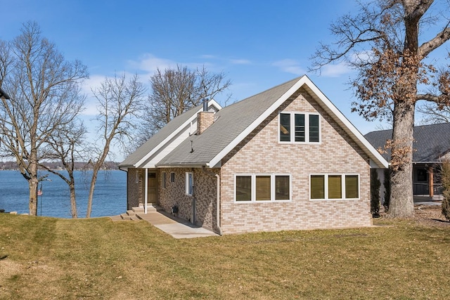 rear view of property with a water view and a lawn