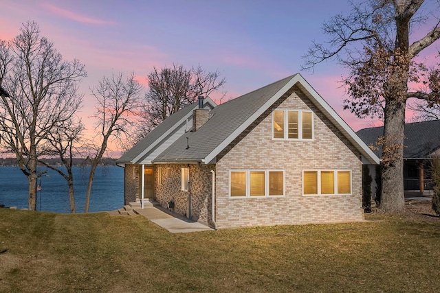 back house at dusk with a lawn