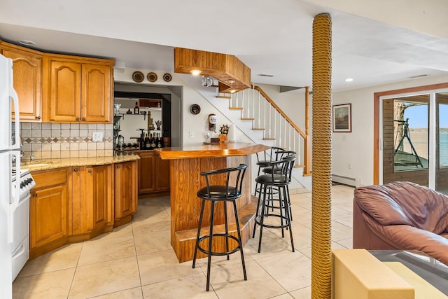 W1188 Spring Grove Rd, Green Lake, WI 54971 - kitchen with light tile flooring, tasteful backsplash, a breakfast bar, and baseboard heating
