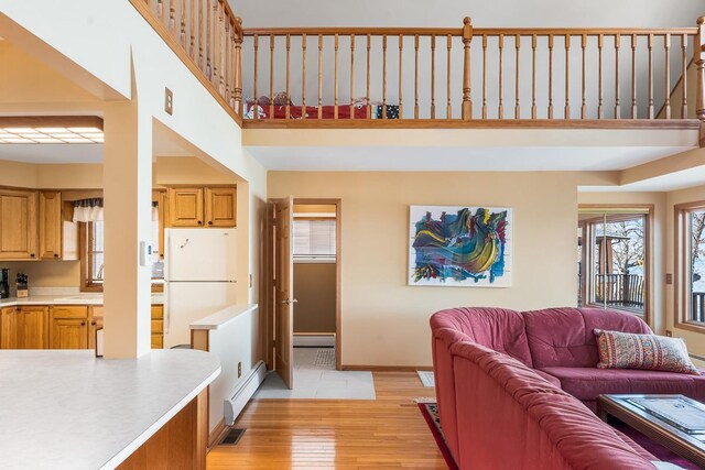 W1188 Spring Grove Rd, Green Lake, WI 54971 - living room with a baseboard radiator, light hardwood / wood-style floors, and a towering ceiling