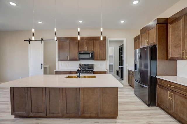 kitchen featuring light hardwood / wood-style flooring, stainless steel appliances, and an island with sink