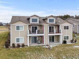 rear view of house with a patio, a balcony, and a yard