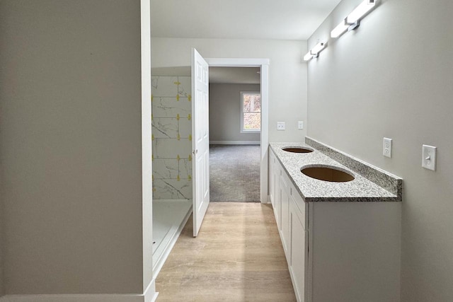 bathroom with walk in shower, vanity, and hardwood / wood-style floors