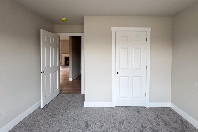 unfurnished bedroom with a closet and dark carpet