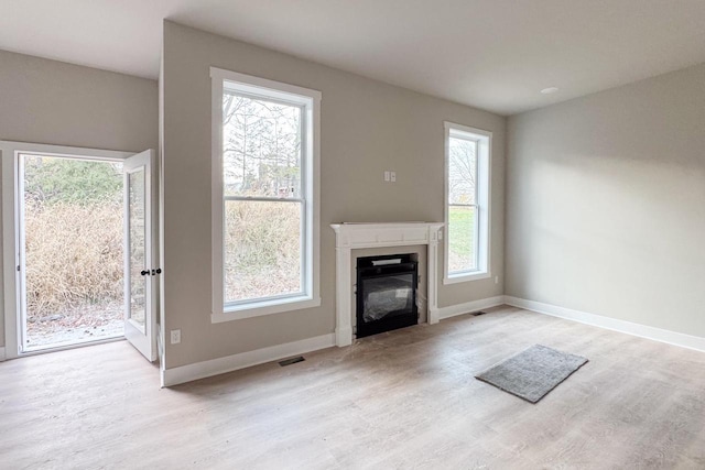 unfurnished living room with light hardwood / wood-style flooring and a healthy amount of sunlight