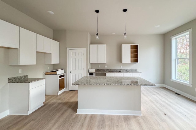 kitchen featuring white cabinetry, pendant lighting, light hardwood / wood-style floors, and a kitchen island