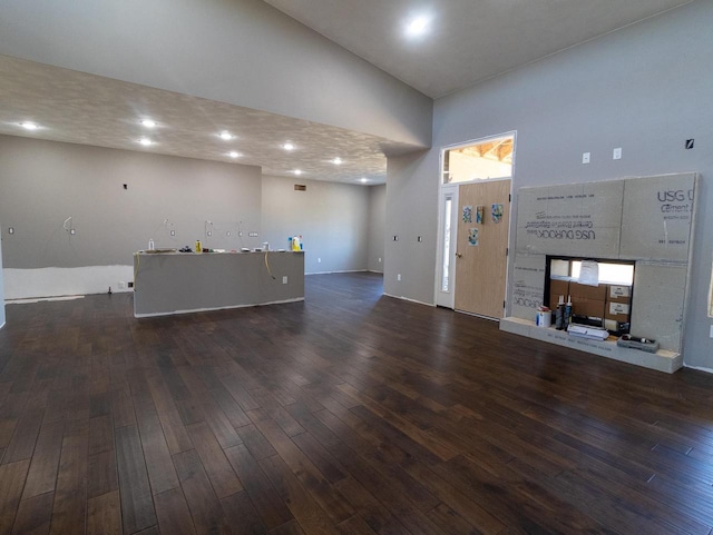 unfurnished living room with a towering ceiling and dark hardwood / wood-style flooring