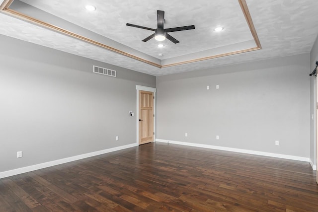 empty room featuring ceiling fan, a textured ceiling, dark hardwood / wood-style flooring, and a tray ceiling