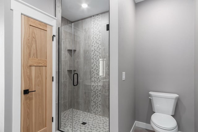 bathroom featuring a shower with shower door and toilet