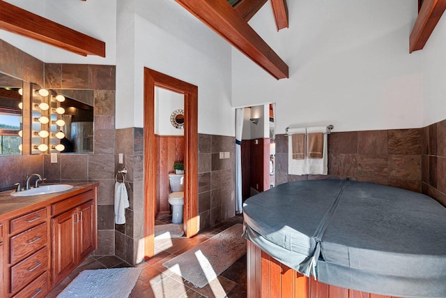 bathroom featuring beamed ceiling, tile flooring, toilet, and tile walls