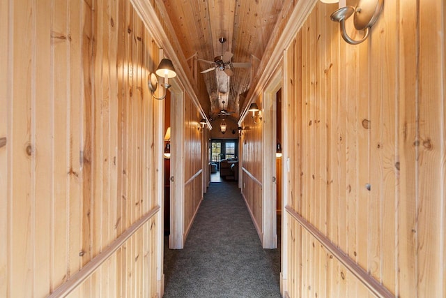 hall with dark colored carpet, wood walls, and wooden ceiling