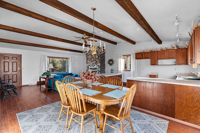 dining room featuring a textured ceiling, wood-type flooring, ceiling fan with notable chandelier, and a fireplace