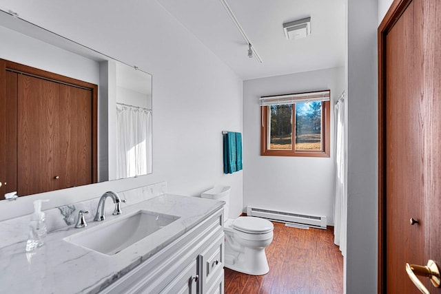 bathroom with toilet, vanity, hardwood / wood-style flooring, and a baseboard heating unit