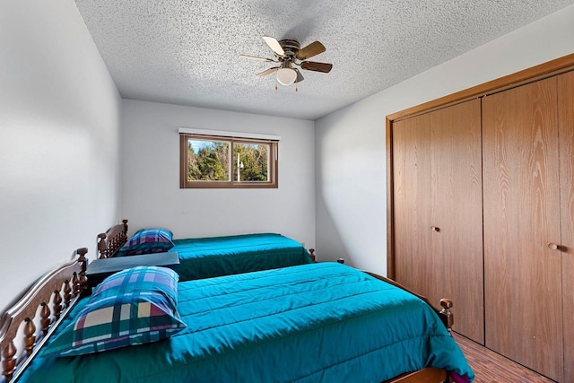 bedroom featuring wood-type flooring, ceiling fan, a textured ceiling, and a closet