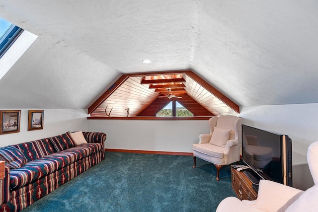 interior space featuring vaulted ceiling with skylight, a textured ceiling, ceiling fan, and dark colored carpet