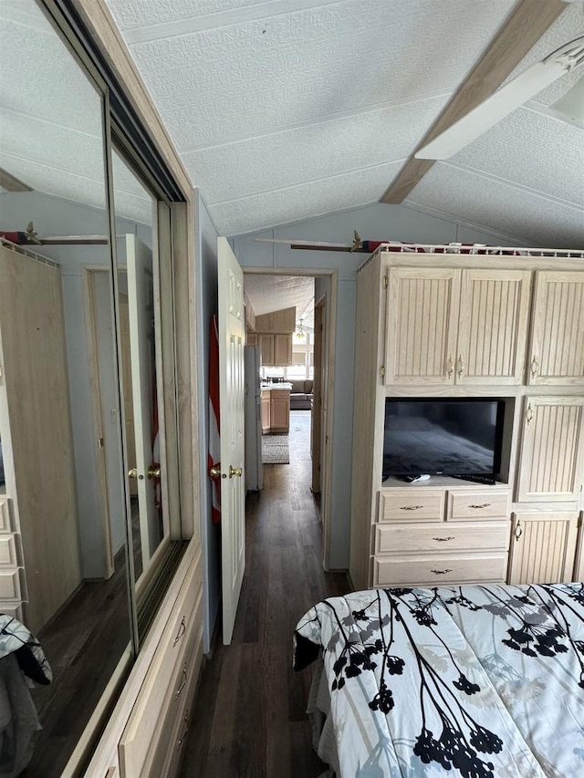 bedroom with a textured ceiling, a closet, vaulted ceiling, and dark wood-type flooring