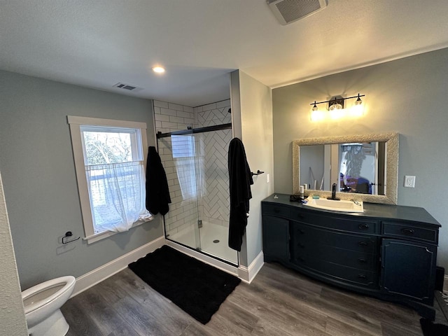 bathroom with a shower with door, hardwood / wood-style floors, toilet, and vanity