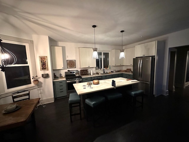 kitchen featuring a breakfast bar area, hanging light fixtures, white cabinets, and appliances with stainless steel finishes