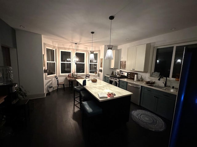 kitchen with dark hardwood / wood-style floors, a kitchen bar, sink, stainless steel appliances, and white cabinets